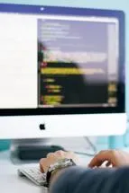 person typing at computer displaying code