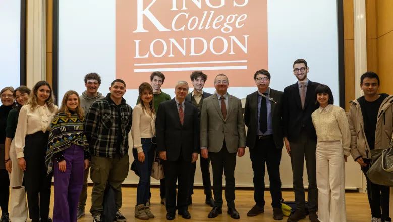 A group of people smiling in front of a projector.