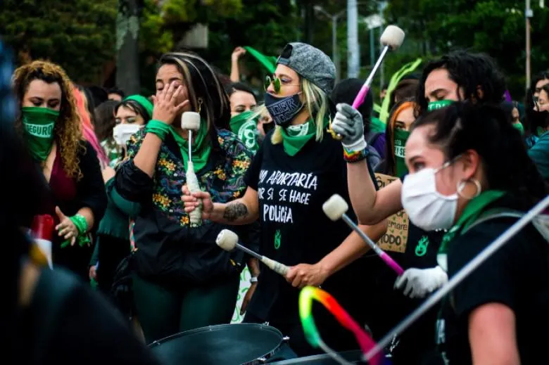 A group of women in black t-shirts and green neckerchiefs join a protest.