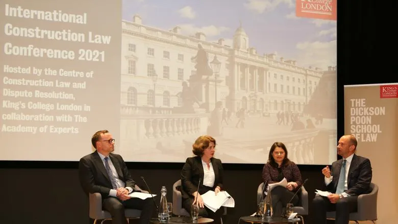 A panel of four people are sitting on a stage in front of a projection of Somerset House