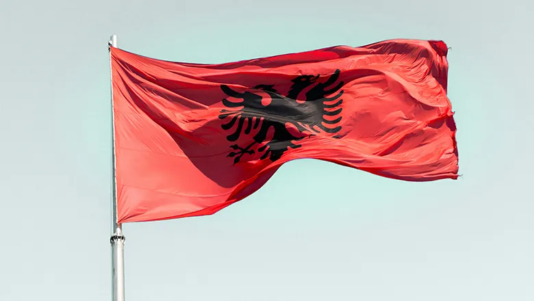 The flag of Albania flying in the wind against a clear sky