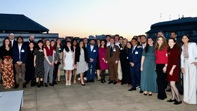 A crowd of thirty people in dinner attire, in the open air.