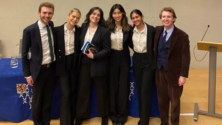 A smiling group of students with their coaches following a moot competition