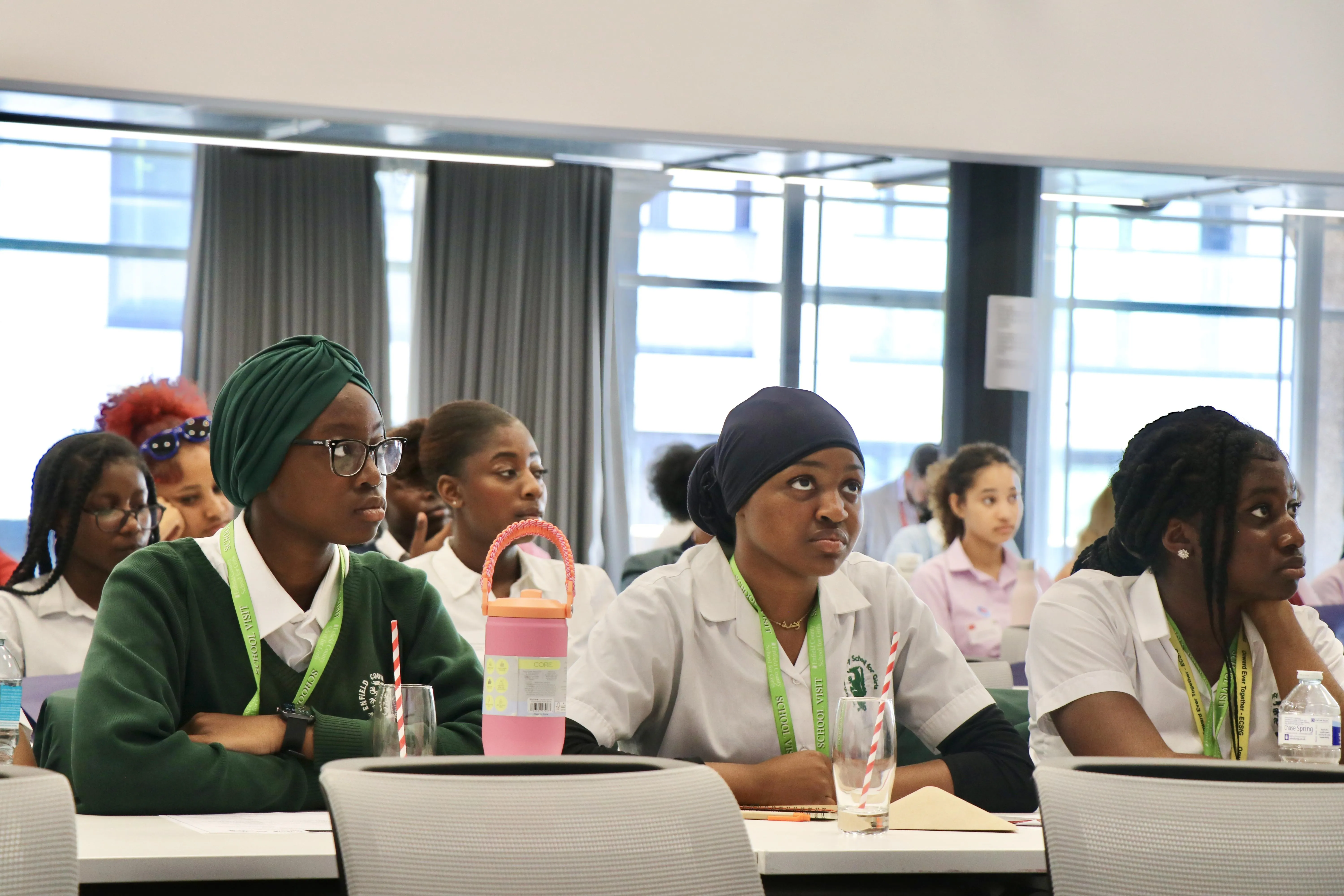 A close shot of three of the students with some students also in the shot.