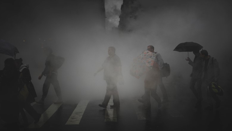 A line of people walk over a pedestrian crossing engulfed in fog
