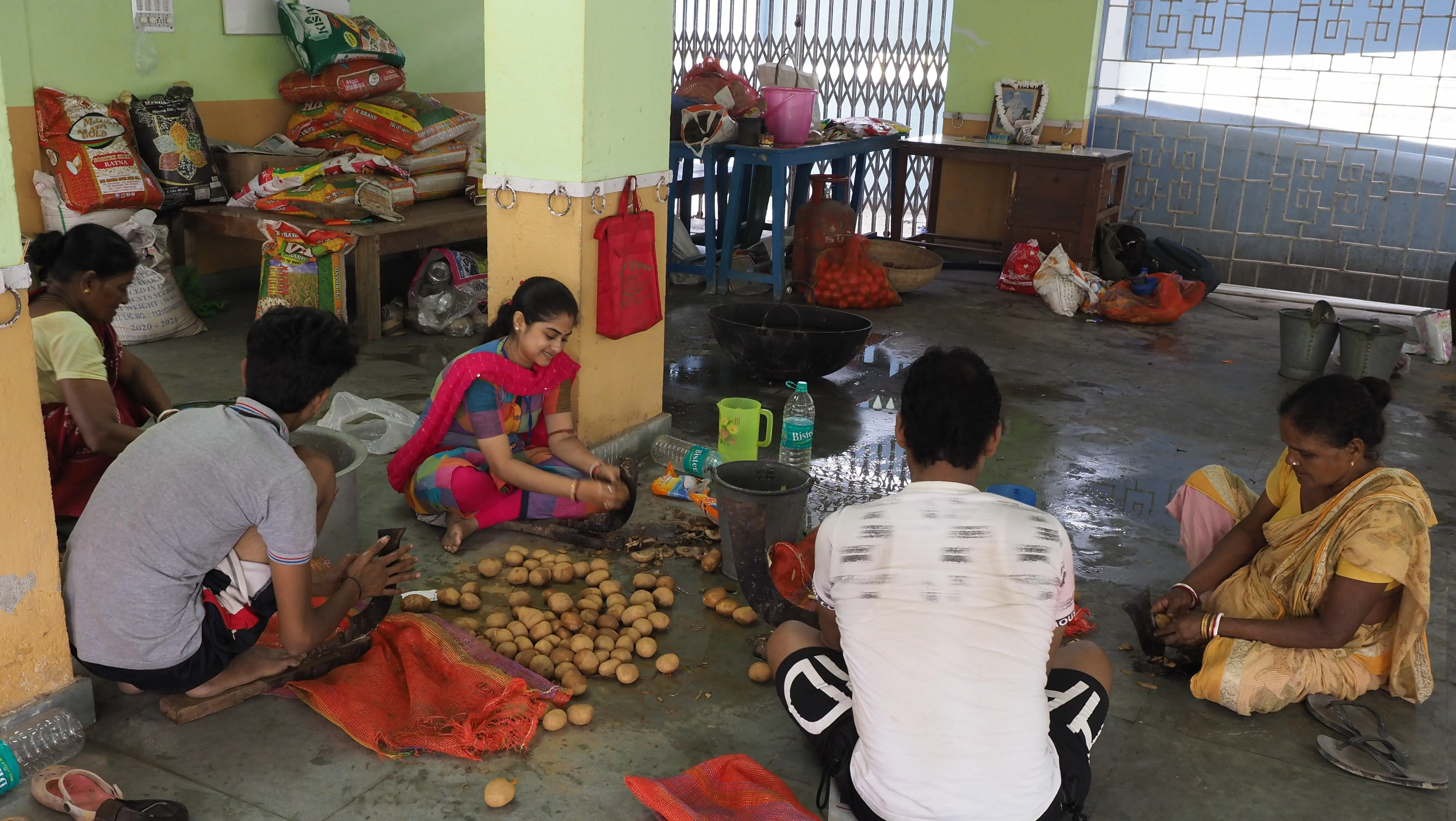 Four men and women are crouching on the floor, sorting food at a flood relief project.