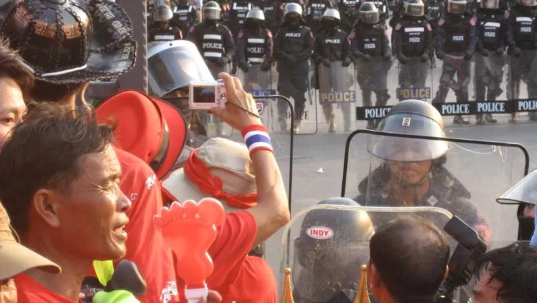 Protestors in red clothes faces a line of riot police