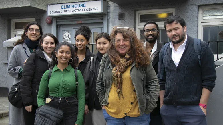 A group shot of nine men and women outside a small community centre.