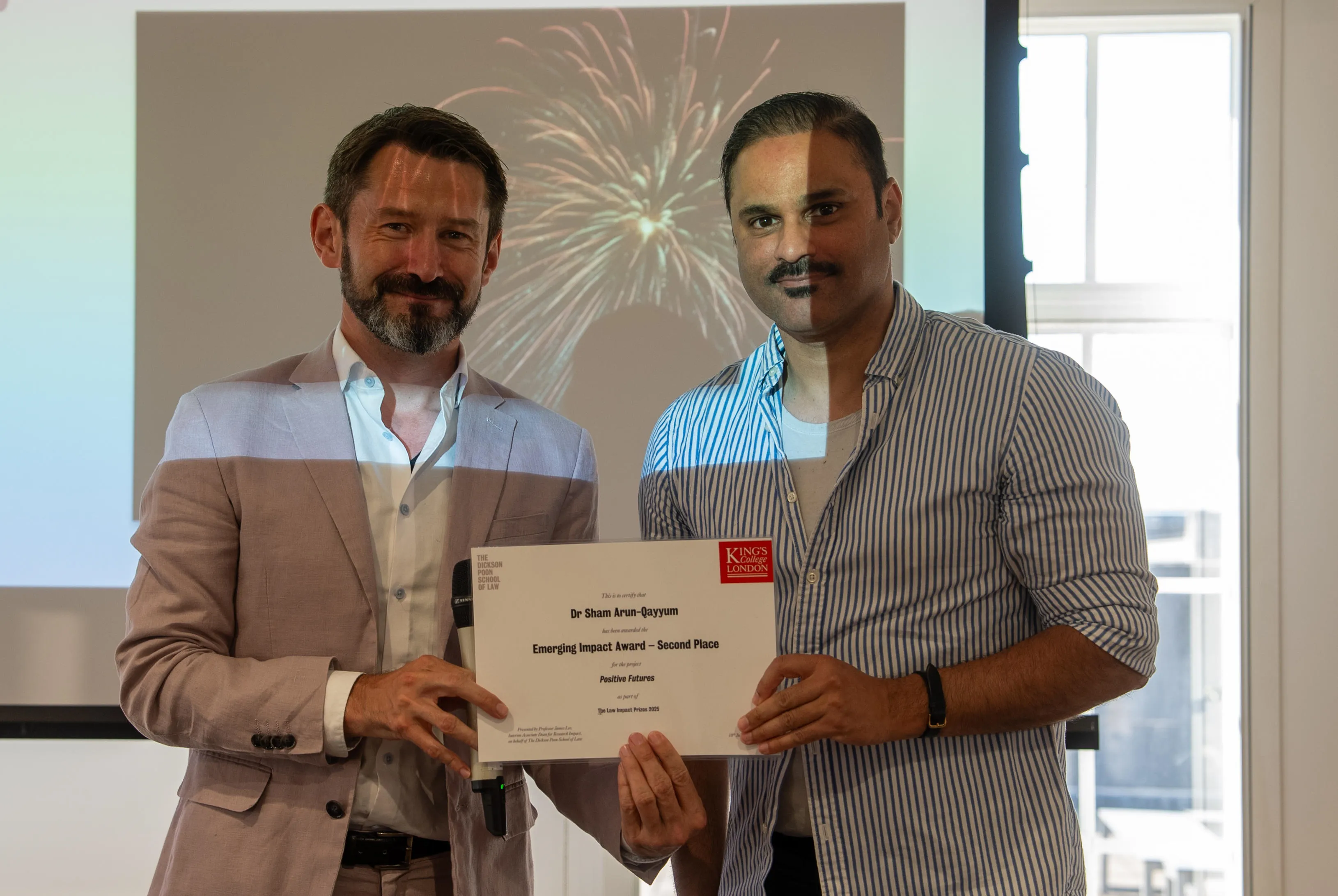 two people standing holding an impact prize certificate