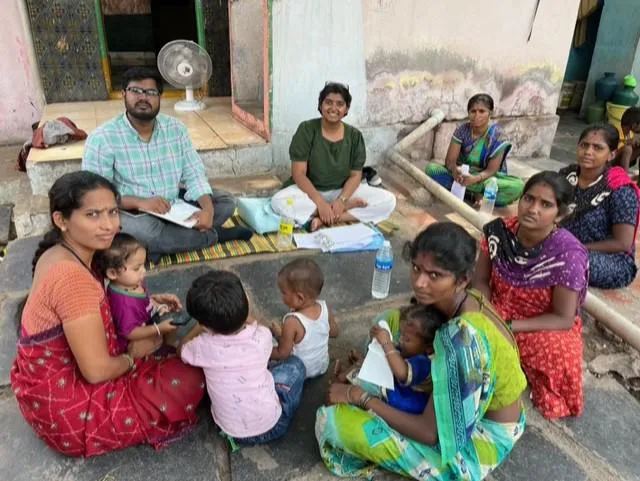Women with children and a man sitting down, looking at the camera.