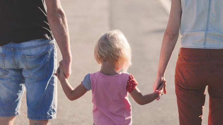 three members of a family holding hands with their backs to us