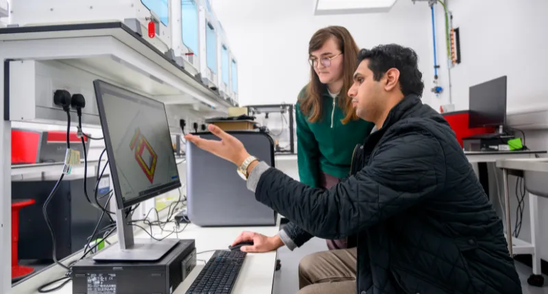 A King's academic describing a 3D model displayed on a computer screen to a second academic.