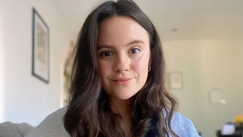 Lily is a woman with long brown hair. She is wearing a white blouse.