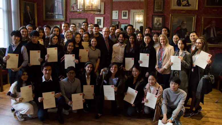 Principal Ed Byrne stands in a large group of scholarship recipients all holding certificates