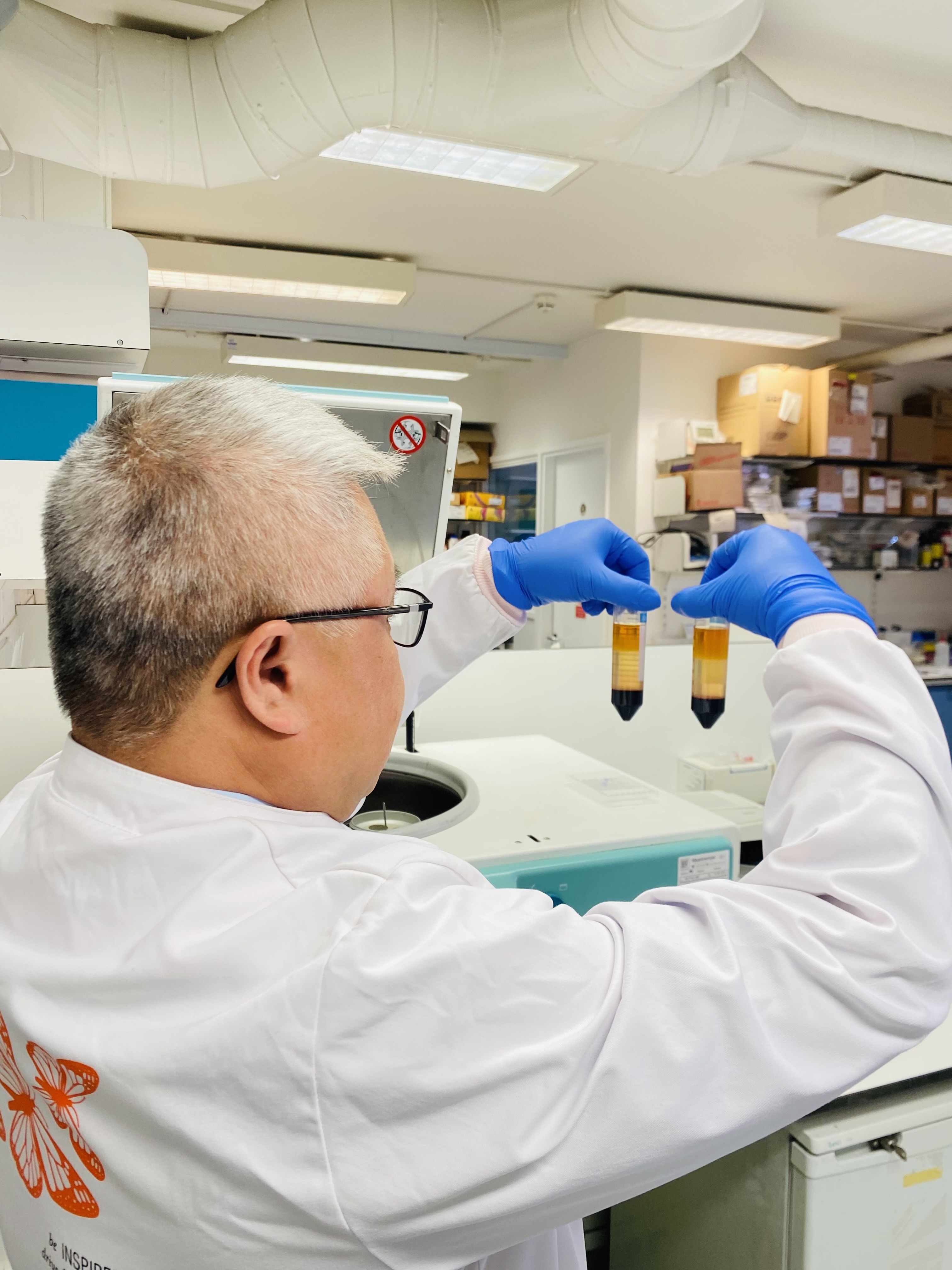 a person in a lab coat looking at two test tubes