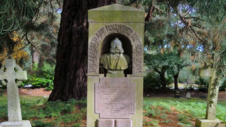 An image of Dr Leitner's grave, with a bust of his head in a wooded, green graveyard
