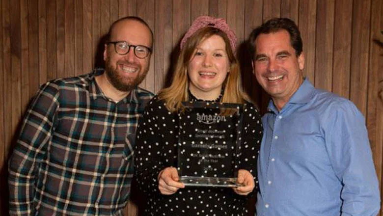Three people hold an award and smile