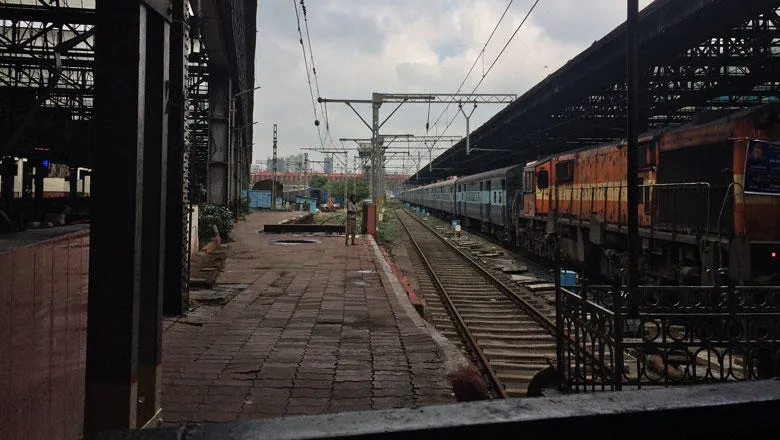 A man beckons to the photographer at a train station