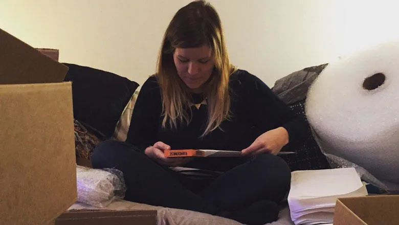 A woman sits cross legged with packaging materials, packing games