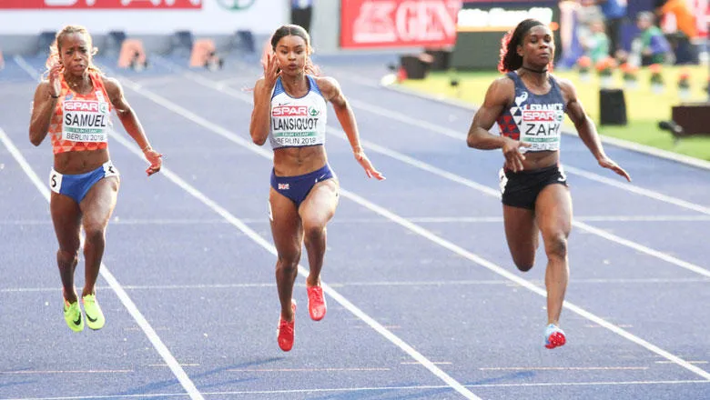 Three female athletes run down a track