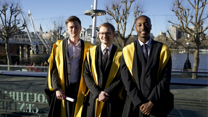Graduates standing in front of the thames