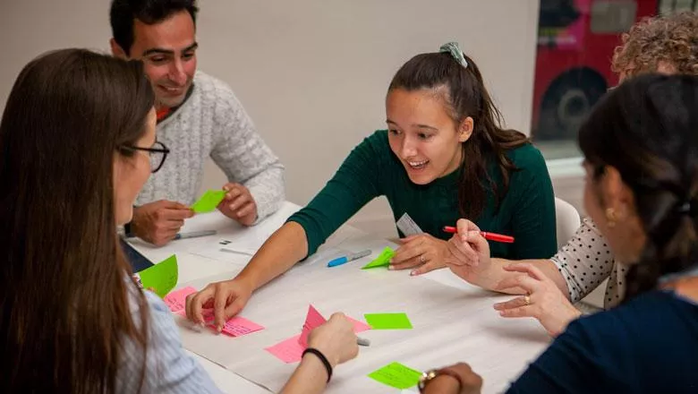 A group chats and arranges brightly coloured post-it notes