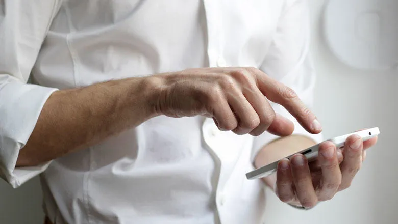 man wearing a white shirt holding a white Android smartphone