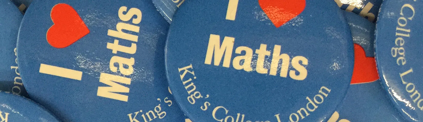 Close up of a pile of blue 'I heart maths' badges from King's