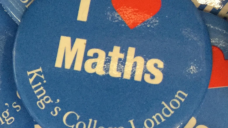 Close up of a pile of blue 'I heart maths' badges from King's