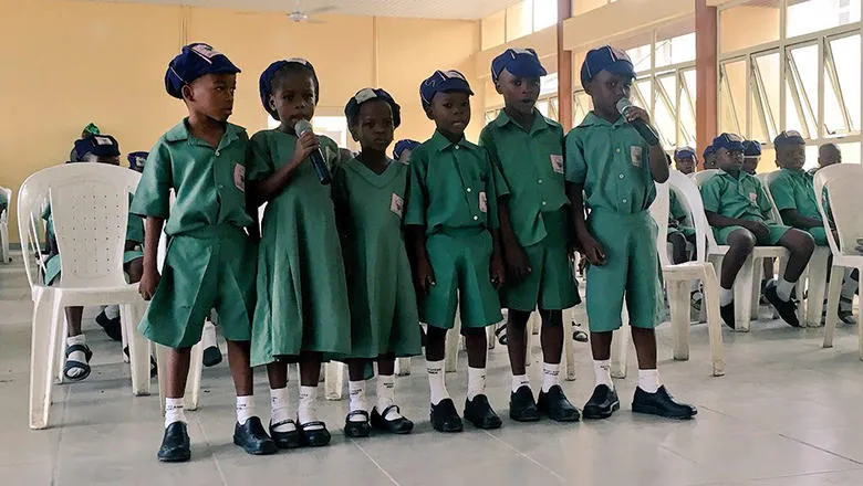 6 schoolchildren lined up, singing or giving a presentation