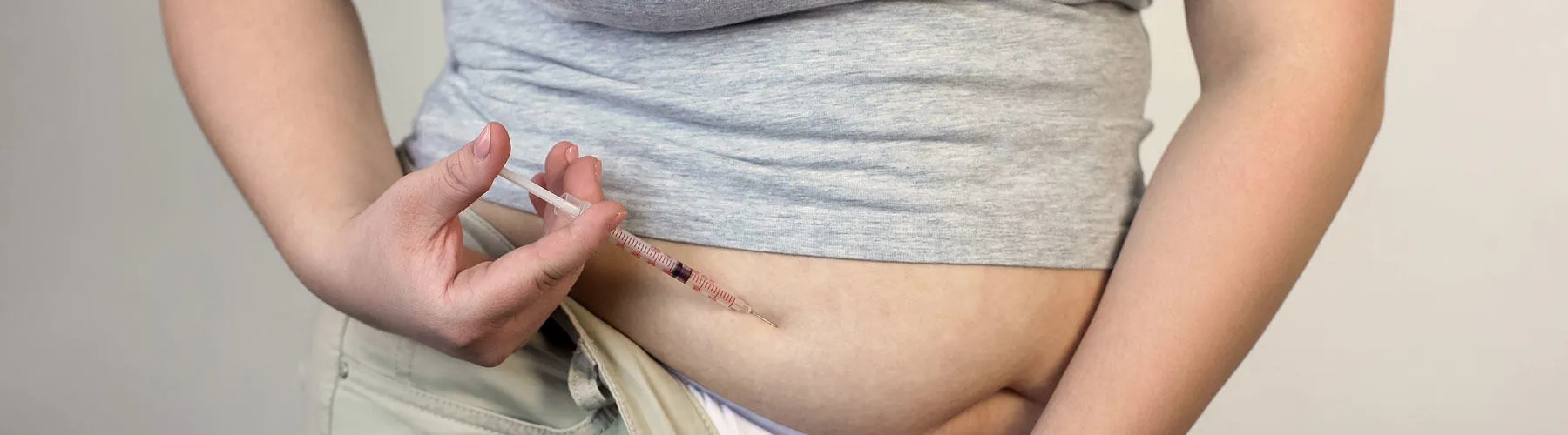 Plus size woman injecting insulin into stomach
