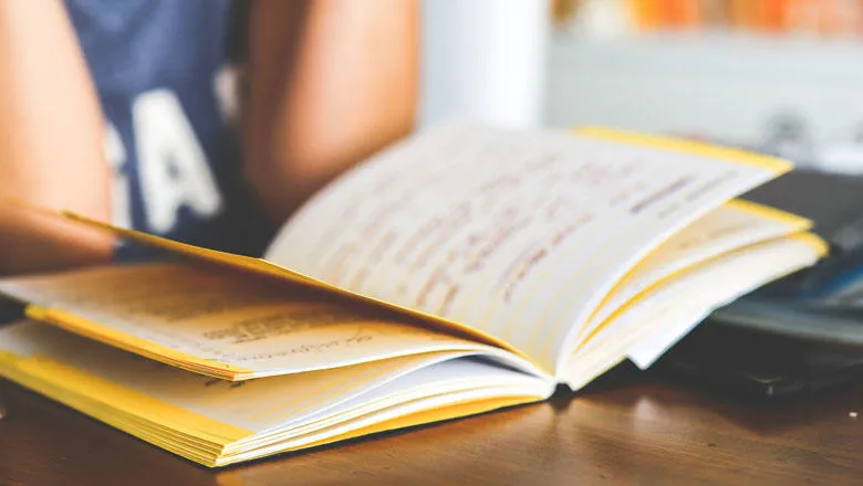 Person reading a yellow book at a desk