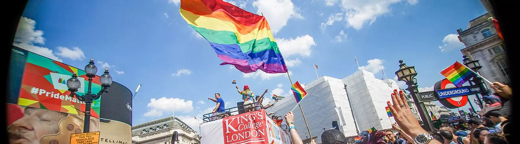 The King's logo on a pride bus, with a giant rainbow flag flying above