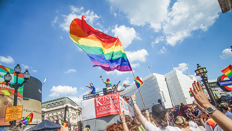 The King's logo on a pride bus, with a giant rainbow flag flying above