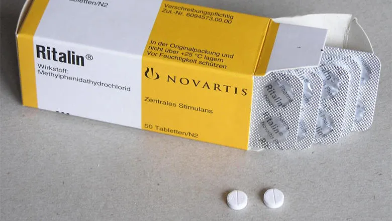 Box of Ritalin with two tablets laying beside it on the table