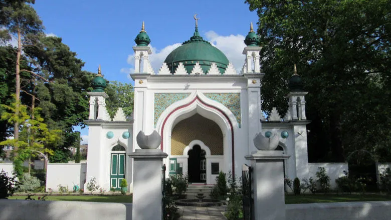 The Shah Jahan mosque, under blue sky surrounded by green trees