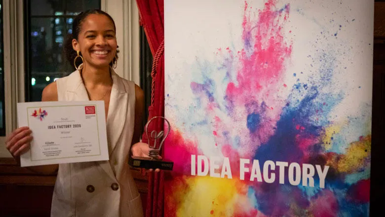 Josephine smiles next to Idea Factory banner