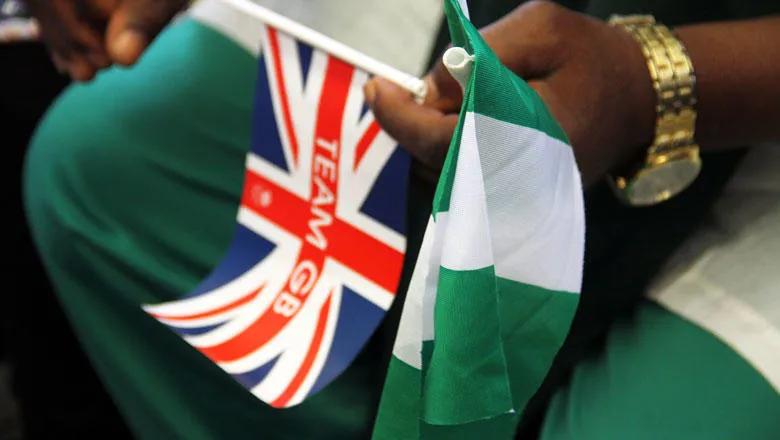 man holding the Union Jack and Nigerian flag in his hands