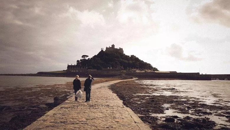 Two people walk down the tidal path at St Michael's Mount in Cornwall