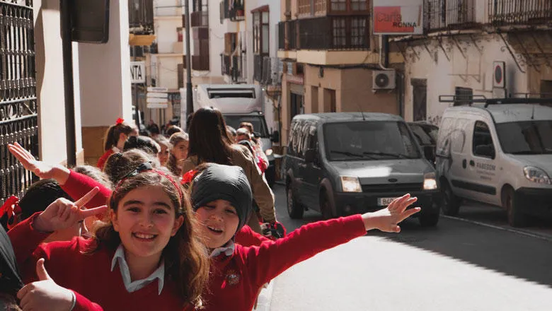 Schoolchildren wave and smile at the camera