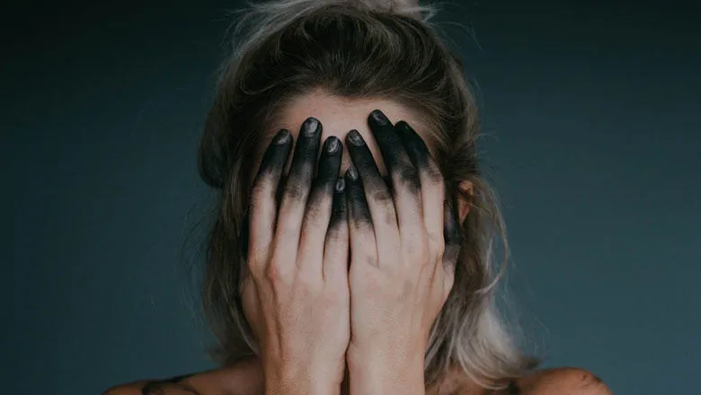 Woman covering face with ink stained hands