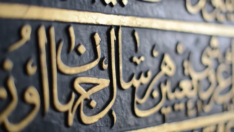 Picture of Arabic text written in gold colour on black background.