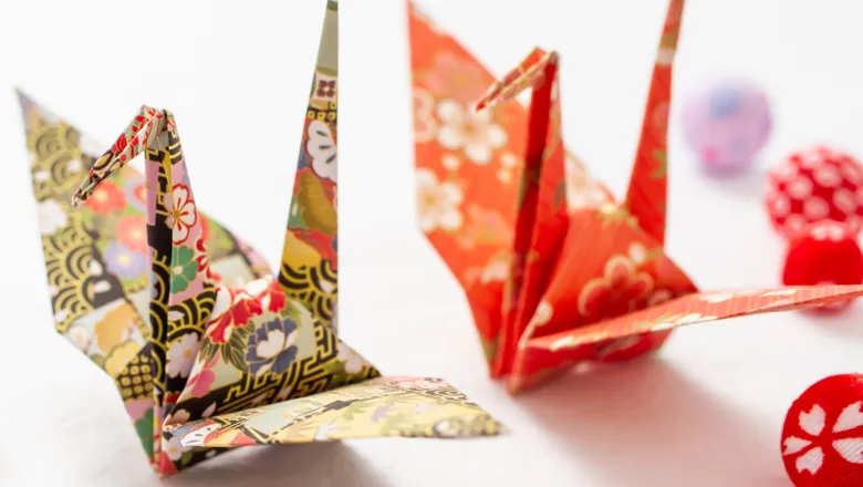 Two Origami swans, one behind the other, made using Origami paper.