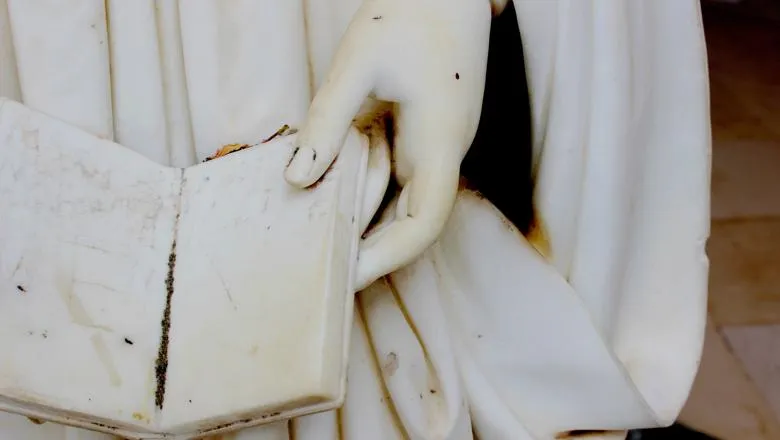 Detail of a statue holding an open book.