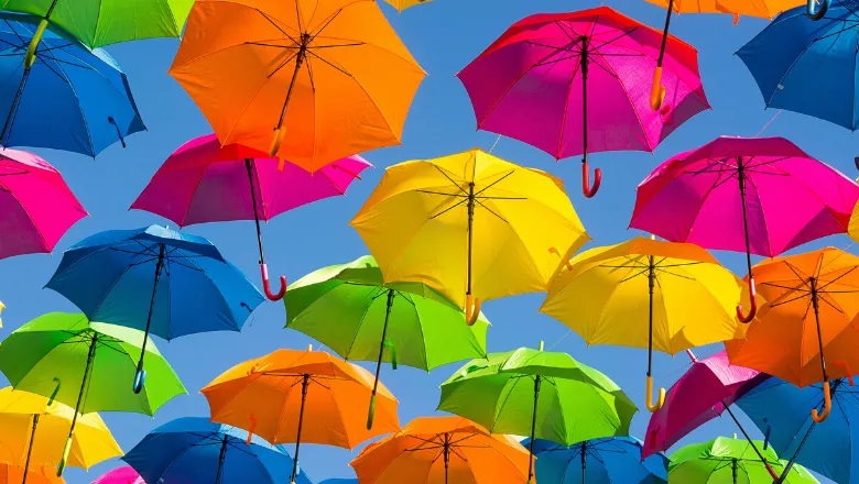 Many umbrellas of different colours over a blue sky