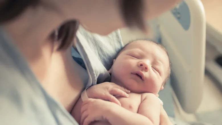 New born baby boy resting in mothers arms.