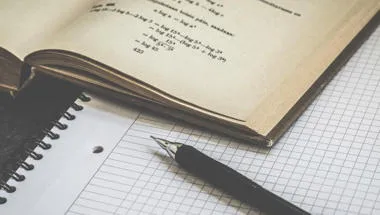 Equations in book, pen and notebook