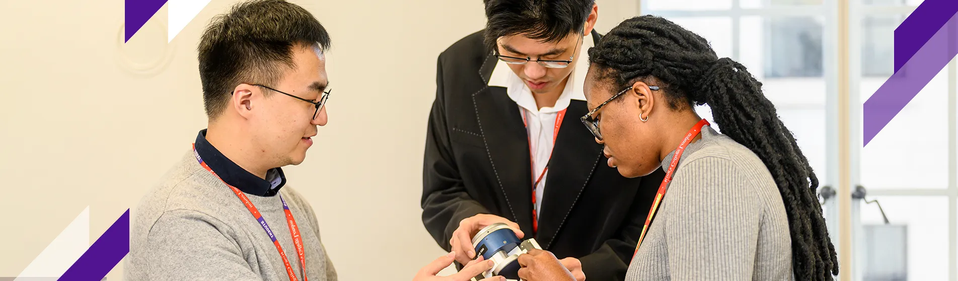 Three PhD students work together on a piece of robotics equipment