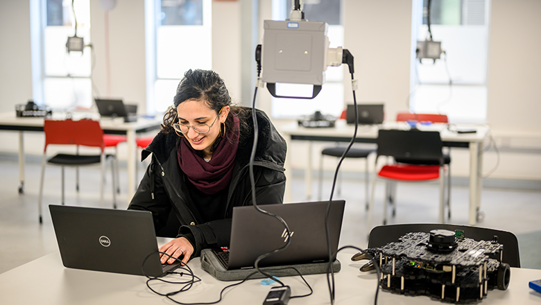 Student programming on two laptops