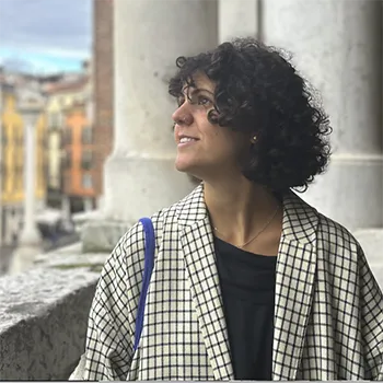 A woman with curly hair smiles as she looks up at the sky